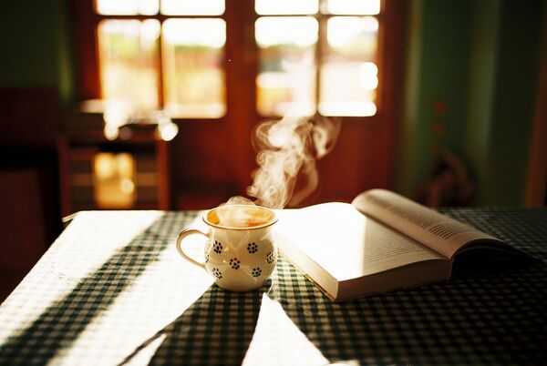 Libro abierto junto a una bebida caliente en un ambiente acogedor